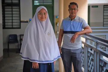KEBANGGAAN BAPA: Nadiah (bersama bapanya, Encik Mohamed Rafi Mohamed), merupakan kumpulan pertama seramai 25 pelajar Madrasah Aljunied Al-Islamiah yang menduduki peperiksaan IBDP tahun lalu dan berjaya meraih keputusan yang amat memberangsangkan. - Foto BH oleh MARK CHEONG