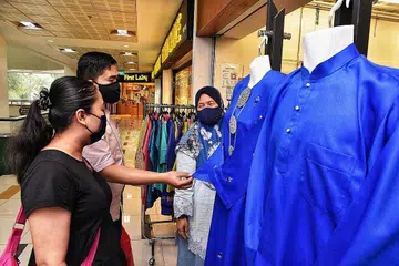 LAYAN PELANGGAN: Pekerja I'z Fashion by Anisah Collection, Cik Faridah Ahmad (kanan), melayani beberapa pelanggan di Tanjong Katong Complex. - Foto BH oleh DESMOND WEE