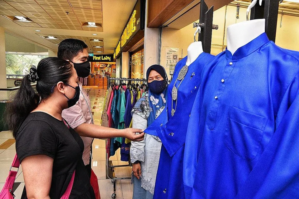 LAYAN PELANGGAN: Pekerja I'z Fashion by Anisah Collection, Cik Faridah Ahmad (kanan), melayani beberapa pelanggan di Tanjong Katong Complex. - Foto BH oleh DESMOND WEE
