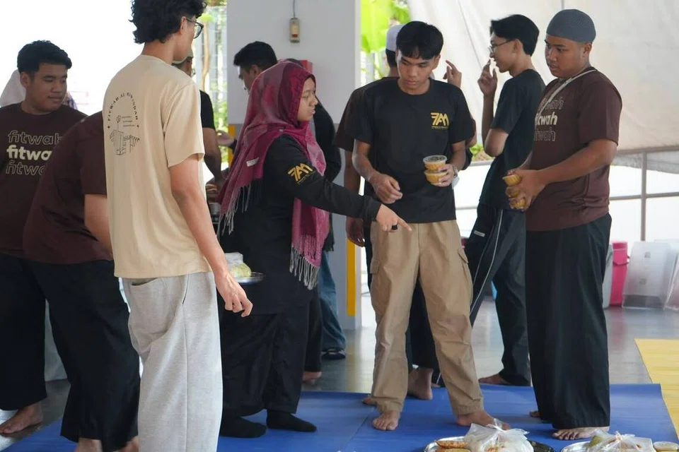 Cik Amirah Adawiyah Mohammad Fauzy (empat dari kiri) dan Encik Firhan Hairul Isham (tiga dari kanan) bersama-sama belia lain membantu menyediakan juadah berbuka puasa untuk para jemaah semasa acara ‘Youth-in-Charge Day’ pada Ramadan.