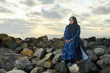 Cik Juliah Bee Abdul Latiff duduk di batu-batu di Pantai Ujong Karang, Meulaboh, Aceh, sambil mengenang masa beliau menyertai misi membangun semula Aceh dari 2005 hingga 2009 sebagai kakitangan Mercy Relief waktu itu.
