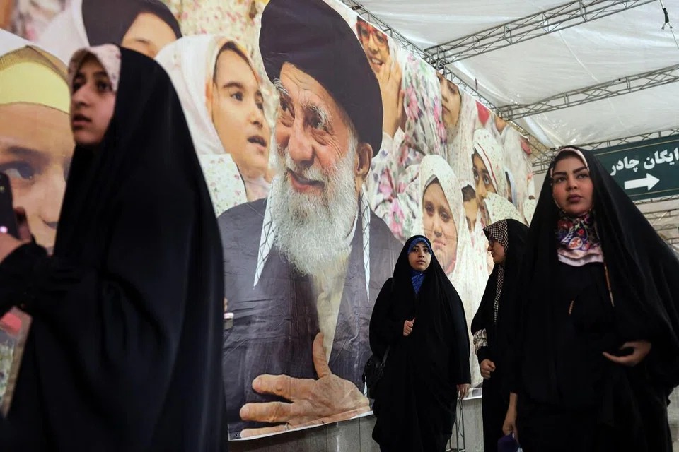 Wanita Iran berjalan melepasi sepanduk memaparkan potret Pemimpin Tertinggi Iran, Ayatollah Ali Khamenei, semasa pameran reka bentuk fesyen Iran-Islam di Masjid Agung Imam Khomeini di Teheran pada 22 Februari 2026.