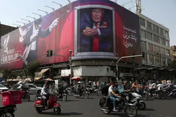Orang ramai memandu berhampiran papan iklan memaparkan Presiden Amerika Syarikat, Encik Donald Trump, di sebuah bangunan di Teheran, Iran, pada 31 Ogos 2026. Ketegangan antara Amerika dan Iran kembali memuncak selepas tentera Amerika melancarkan serangan ke atas sasaran ketenteraan Iran, sebelum Teheran membalas dengan serangan peluru berpandu dan dron terhadap pangkalan serta aset Amerika di rantau itu