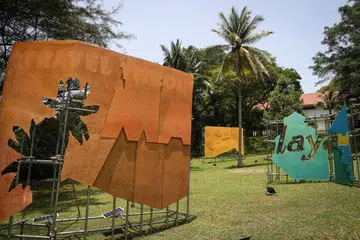 KARYA MENARIK: Seniman, Encik Hilmi Johandi, menyusun satu siri cetakan bersaiz papan iklan yang dibina daripada serpihan dan kolaj iklan perjalanan awal abad ke-20 Kereta Api Negeri-Negeri Melayu Bersekutu (1901–1948).