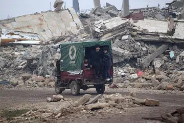 SEMUA RUNTUH: Kanak-kanak ini menaiki kenderaan di tengah-tengah bangunan yang runtuh di bandar al-Rai town, utara Aleppo. - Foto REUTERS