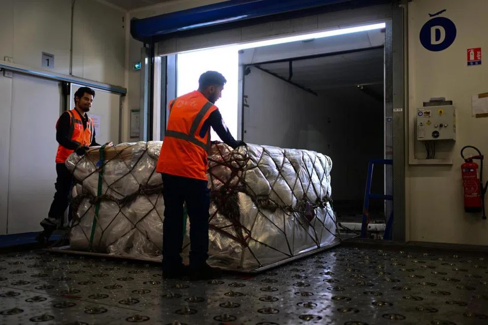 Dua pekerja sedang memuatkan kargo farmaseutikal ke dalam van di kemudahan kargo World Flight Services (WFS) di Lapangan Terbang Charles de Gaulle, Paris.