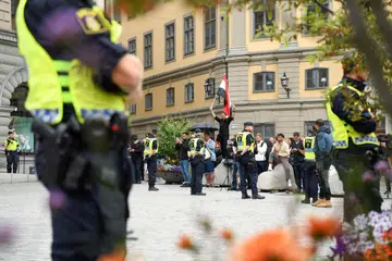 BERJAGA-JAGA: Anggota polis berjaga-jaga berdiri berdekatan penunjuk perasaan di Stockholm, Sweden. Dua lelaki telah membakar Al-Quran di luar parlimen di Stockholm, menurut laporan AFP.
