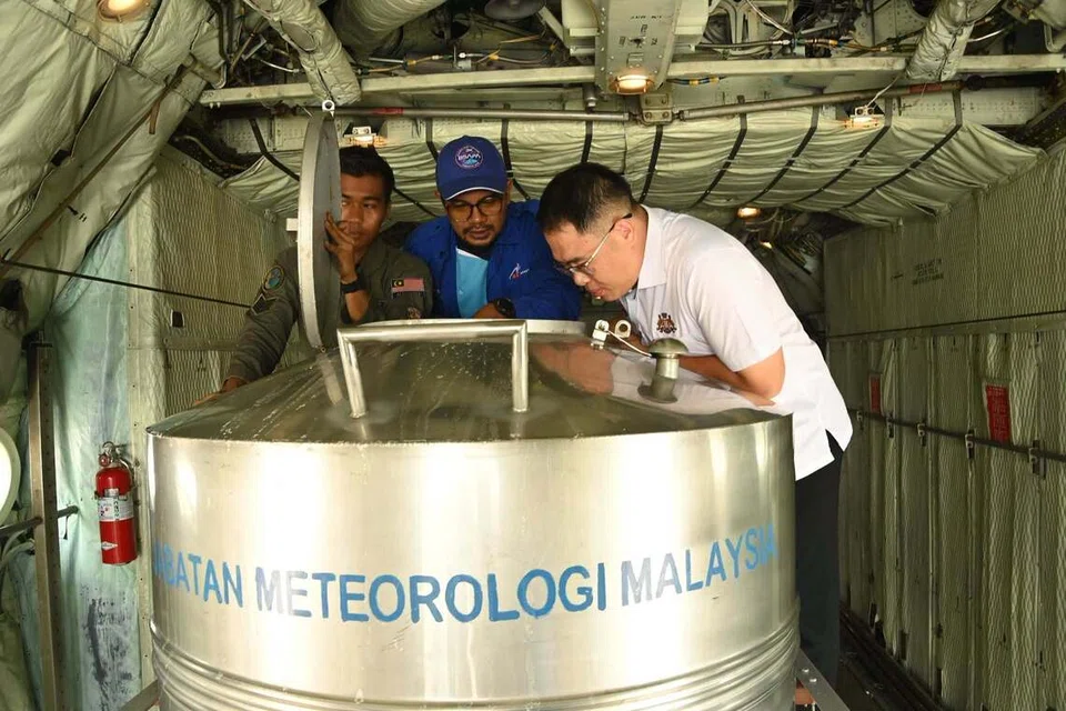 Pengerusi Jawatankuasa Kesihatan dan Alam Sekitar Johor, Encik Ling Tian Soon (kanan), melihat tangki berisi air garam yang diharapkan dapat membantu dalam mengurangkan kepekatan partikel jerebu di udara.