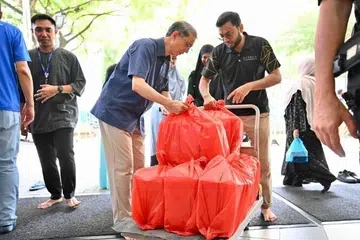 Profesor Madya Dr Muhammad Faishal Ibrahim (kiri), menerima hidangan nasi beriani yang akan diagihkan kepada sekitar 460 benefisiari, terdiri daripada bekas banduan dan mereka yang terjejas akibat penyalahgunaan dadah, pada Jun lalu.