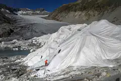 PERLU PRIHATIN: Seorang lelaki bekerja di Rhone Glacier, berhampiran Gletsch, di Switzerland. Sebahagian bongkah air batu itu terpaksa diselubung untuk mencegahnya daripada terus cair akibat cuaca yang kian panas. Bongkah batu yang cair boleh menyebabkan paras air laut meningkat dan seterusnya menyebabkan banjir di merata dunia. 