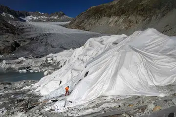 PERLU PRIHATIN: Seorang lelaki bekerja di Rhone Glacier, berhampiran Gletsch, di Switzerland. Sebahagian bongkah air batu itu terpaksa diselubung untuk mencegahnya daripada terus cair akibat cuaca yang kian panas. Bongkah batu yang cair boleh menyebabkan paras air laut meningkat dan seterusnya menyebabkan banjir di merata dunia. 