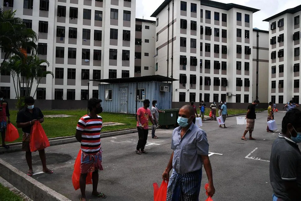 Pekerja asing mematuhi langkah jarak selamat sewaktu menunggu giliran mendapatkan makanan di sebuah dormitori di Tampines pada 3 Jun 2020. - FOTO: KUA CHEE SIONG