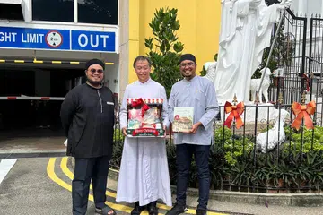 PUPUK HARMONI: Dua wakil daripada Masjid Omar Kampong Melaka, Ketua Dakhwah dan Pembangunan Sosial masjid, Ustaz Abdillah Amirnordin (kanan); dan pegawai masjid, Ustaz Muhammad Khairulanwar Shamsuri (kiri), melawat Gereja Sacred Heart di Tank Road, yang dihoskan Paderi Stephen Yim (tengah).