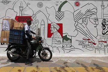 Seorang penunggang motosikal melalui mural di sebuah jalan di Tehran pada 21 Julai ketika konflik antara Iran dan Amerika Syarikat terus memuncak. Pada hari berikutnya, Dewan Perwakilan Amerika Syarikat meluluskan rangka kerja bajet bernilai AS$95 bilion dengan sebahagian besar dana diperuntukkan bagi membiayai operasi ketenteraan terhadap Iran, sementara Tehran mendakwa terus menyerang sasaran tentera Amerika Syarikat di rantau Asia Barat.