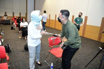 Cik Rahayu Mahzam mengagihkan buku panduan 'Mentor Manual' kepada mentor di acara Amalan Masyarakat (COP) Pejabat Pementoran Belia Yayasan Mendaki pada Sabtu (23 Okt). 