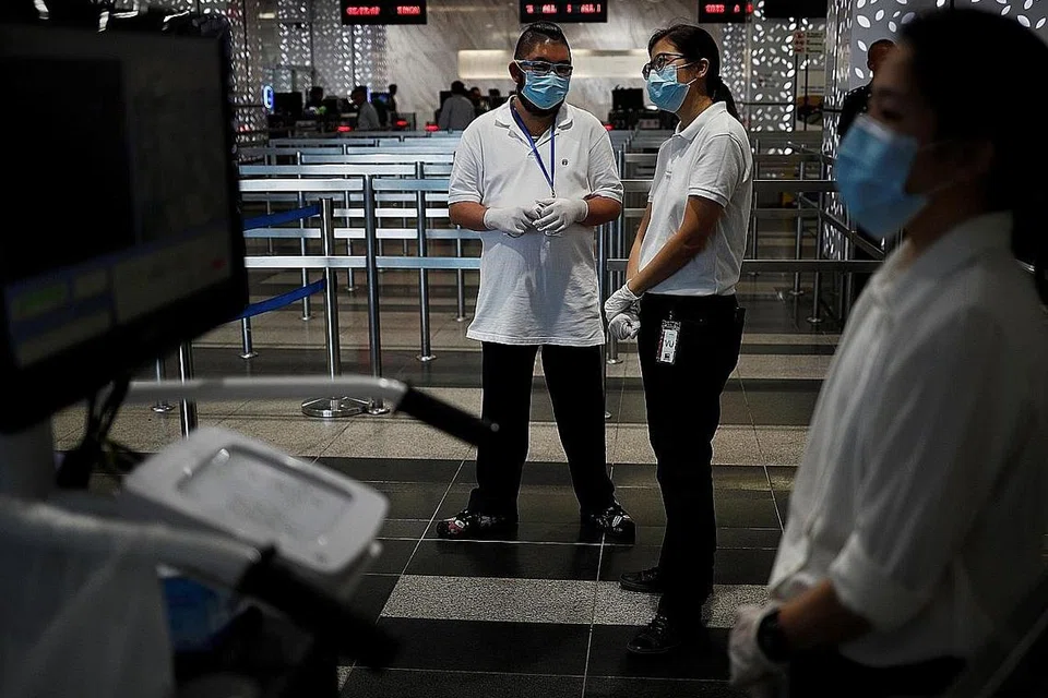 KETELITIAN DALAM PEMERIKSAAN: Kakitangan Penguasa Imigresen & Pusat Pemeriksaan (ICA) menanti pengunjung dari arah laut untuk mengukur suhu badan mereka. - Foto REUTERS