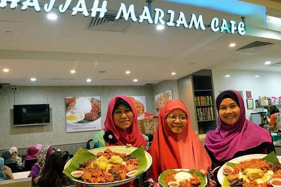 SILAKAN CUBA: Nasi ambeng Hajjah Mariam Cafe yang mempunyai tiga saiz berbeza ditunjukkan (dari kiri) Cik Azidah Kamis, anak bongsu Ustazah Siti Mariam, memegang dulang paling besar; Ustazah Siti Mariam dengan sepinggan nasi ambeng; dan Cik Adhana, anak sulung, dengan dulang saiz sederhana. - Foto-foto KHALID BABA