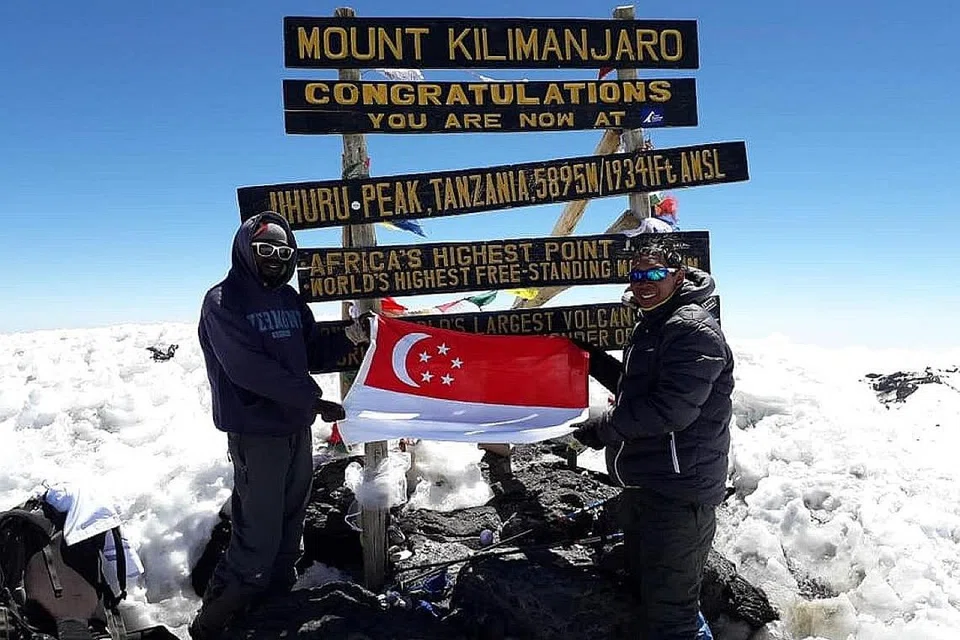 GUNUNG DITAWAN: Kegembiraan penulis (kanan) setelah berjaya tiba di mercu tanda 'Uhuru Peak', puncak tertinggi di benua Afrika. - Foto ihsan MOHAMMAD RAFIE SABARSHAH
