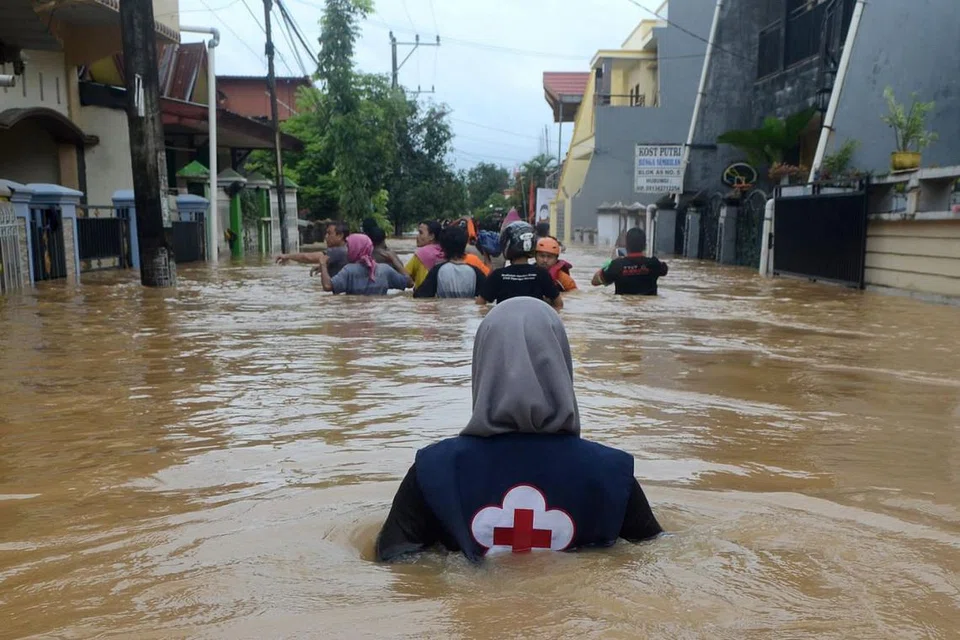HARUNGI CABARAN: Seorang sukarelawan mengharungi banjir di kawasan kediaman di Makassar, Sulawesi Selatan, untuk membantu penduduk yang terjejas akibat banjir. - Foto REUTERS