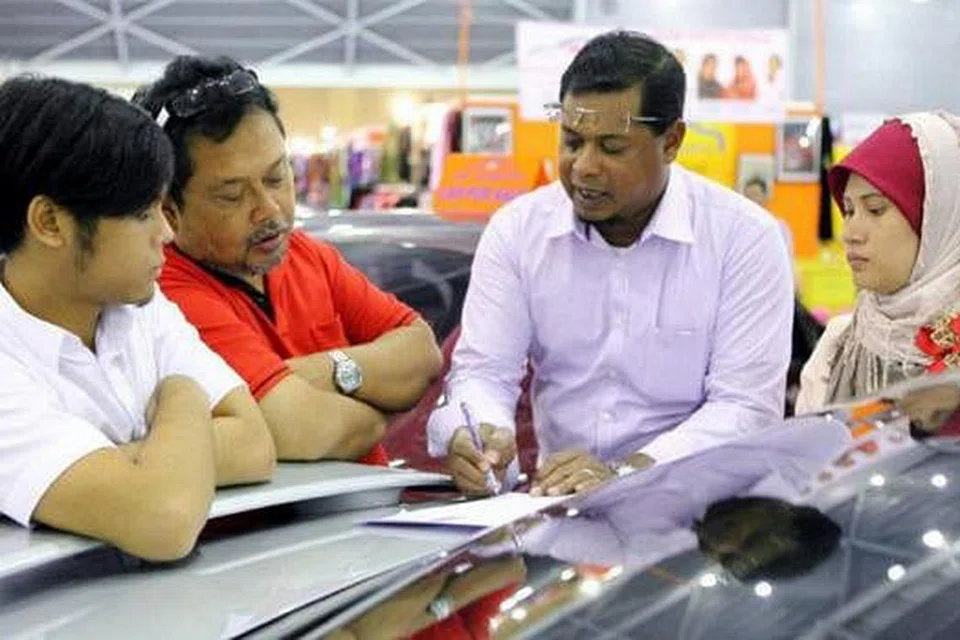 HITUNG DULU: Haji Ismail (dua dari kanan) berbincang dengan pelanggannya mengenai perbelanjaan wang sebelum membeli kereta.- Foto DR KERETA