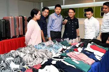 CURI PAKAIAN: Penolong Pesuruhjaya Polis Tan Tin Wee (empat dari kiri) dan pegawai lain yang membantu menumpaskan sindiket dari Vietnam dengan hampir 900 barangan yang dicuri, lebih separuh merupakan coli. - Foto BH oleh KHALID BABA