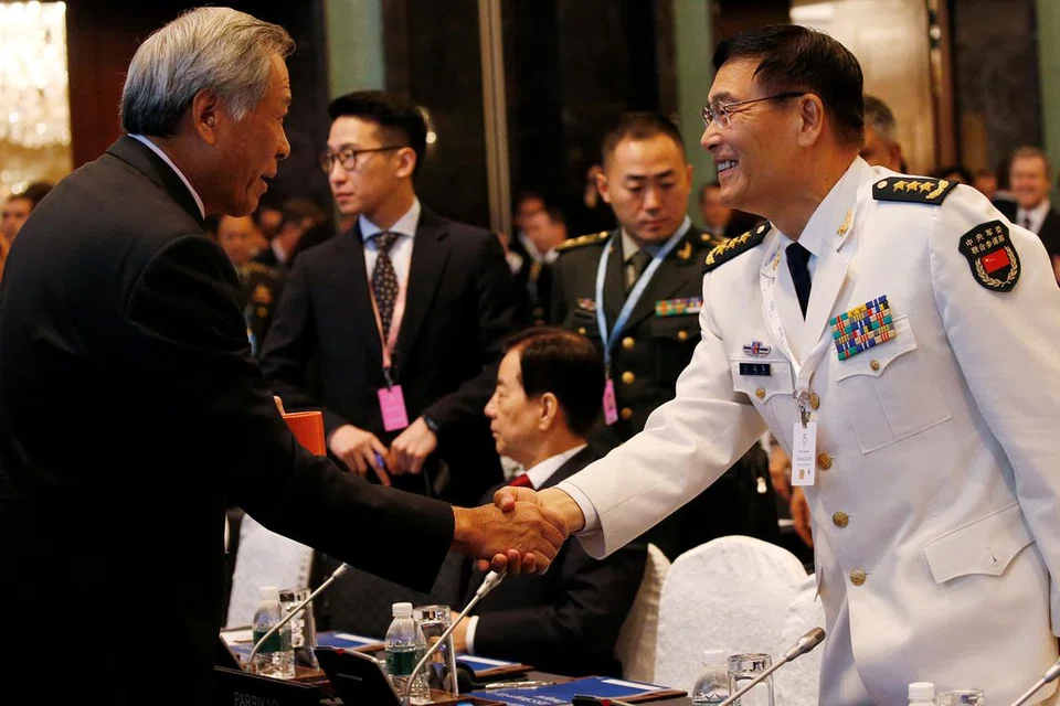 SALAM PERSAHABATAN: Encik Ng (kiri) bersalaman dengan Timbalan Ketua Jabatan Staf Bersama China, Laksamana Sun Jianguo, semasa bertemu di sidang Dialog Shangri-La. - Foto Reuters