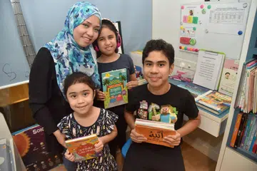 MENDIDIK ANAK AUTISME: Cik Noreen (bertudung biru), mempunyai dua anak autisme - Irfan (berdiri di depan) dan Natasha (memakai headphone). Anak bongsunya, Sofea (di kanan Irfan) tidak mengalami masalah autisme. - Foto BH oleh JASMINE CHOON