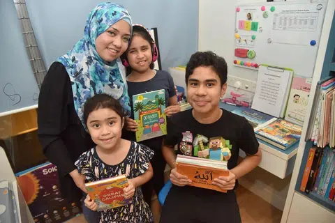 MENDIDIK ANAK AUTISME: Cik Noreen (bertudung biru), mempunyai dua anak autisme - Irfan (berdiri di depan) dan Natasha (memakai headphone). Anak bongsunya, Sofea (di kanan Irfan) tidak mengalami masalah autisme. - Foto BH oleh JASMINE CHOON