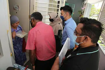 HULUR BANTUAN: Encik Murali (berbaju merah) menghulurkan dua bungkus nasi ayam masakan cef selebriti Syed Shah dan beg cenderahati kepada Cik Gaya Jantan, semalam. Bersama mereka ialah Cik Roszanah Abdul Salim (tiga dari kiri), Ustaz Md Azri Azman (empat dari kiri) dan pengurus Pusat Kesihatan dan Jagaan Siang Muhammadiyah (MHCC) Encik Siddiq Rahim. - Foto PERSATUAN MUHAMMADIYAH