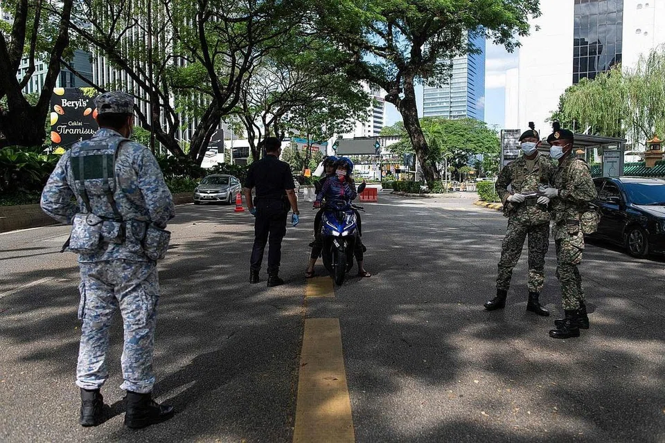 LEBIH TEGAS: Pegawai polis dan tentera Malaysia melakukan pemeriksaan di Kuala Lumpur kelmarin. Daripada memberi nasihat, mereka kini mengambil tindakan lebih tegas bagi melaksana Perintah Kawalan Pergerakan. - Foto AFP