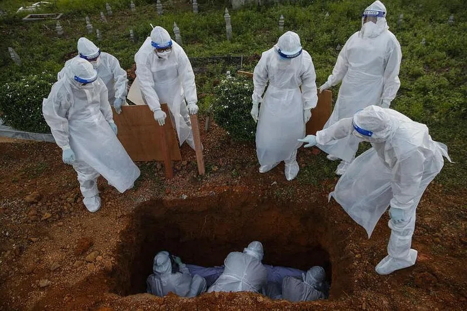 KEADAAN MEMBIMBANGKAN: Pekerja dengan sut bahan berbahaya atau 'hazmat' mengendalikan jenazah yang meninggal dunia kerana Covid-19 di Kuala Selangor. Menurut data pemodelan terkini Kementerian Kesihatan Malaysia, negara itu mungkin melihat lebih 8,000 kes Covid-19 baru sehari menjelang Jun jika orang awam gagal berpandukan undang-undang pengurusan selamat. - Foto EPA-EFE/FAZRY ISMAIL 
