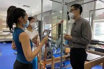 MULA PERLAHAN: Dr Lim Ang Tee (kanan) sedang berbincang dengan seorang pakar fisioterapi mengenai program pemulihan seorang pesakitnya (kiri). - Foto CGH