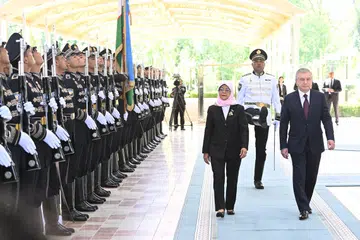 KUNJUNGAN PERTAMA: Presiden Singapura, Puan Halimah Yacob, dan Presiden Uzbekistan, Encik Shavkat Mirziyoyev, memeriksa kawalan kehormatan di Istana Kuksaroy pada Rabu.