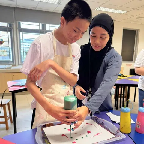 Menurut Cik Nur Aqilah Jamaludin (kanan), yang juga mengetuai kurikulum seni AWWA School @ Bedok secara bersama, seni merupakan kaedah bagi pelajar yang mempunyai autisme untuk berkomunikasi.