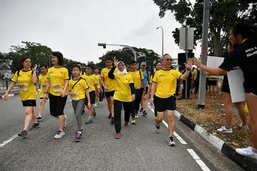 SOKONGAN MASYARAKAT: Presiden Halimah (dua dari kanan) menyertai acara berjalan kaki secara suka-suka sepanjang lima kilometer dalam Larian Penjara Reben Kuning yang ke-11 semalam yang disertai 10,000 pelari dan berjaya memungut dana $125,000. - Foto BH oleh LIM YAOHUI