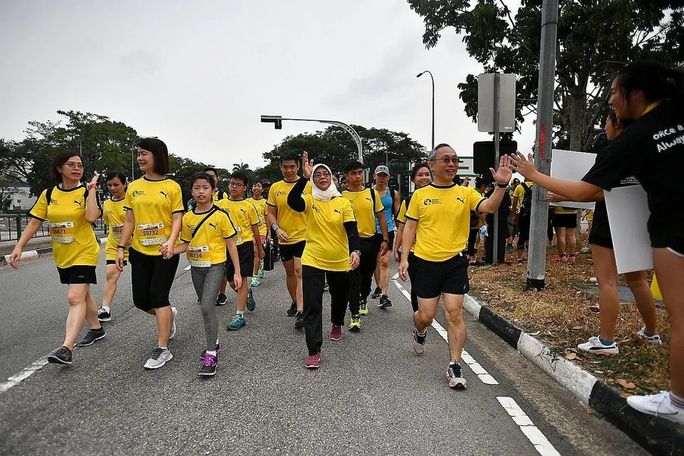 SOKONGAN MASYARAKAT: Presiden Halimah (dua dari kanan) menyertai acara berjalan kaki secara suka-suka sepanjang lima kilometer dalam Larian Penjara Reben Kuning yang ke-11 semalam yang disertai 10,000 pelari dan berjaya memungut dana $125,000. - Foto BH oleh LIM YAOHUI