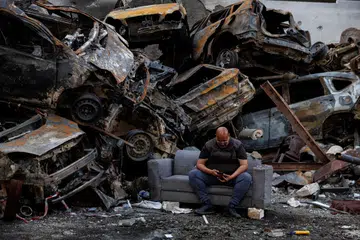 Seorang penduduk yang terselamat daripada serangan Israel duduk di sisi longgokan kereta yang rosak di lokasi serangan udara Israel pada 8 April di Corniche al-Mazraa, Beirut, Lebanon.