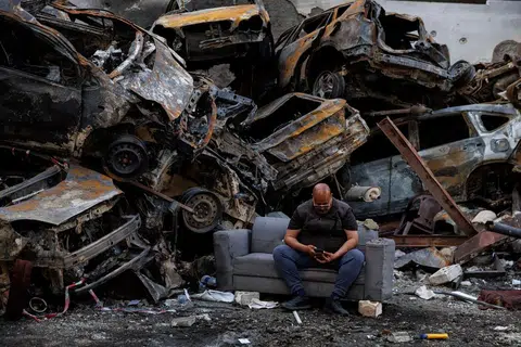 Seorang penduduk yang terselamat daripada serangan Israel duduk di sisi longgokan kereta yang rosak di lokasi serangan udara Israel pada 8 April di Corniche al-Mazraa, Beirut, Lebanon.