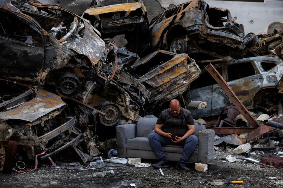 Seorang penduduk yang terselamat daripada serangan Israel duduk di sisi longgokan kereta yang rosak di lokasi serangan udara Israel pada 8 April di Corniche al-Mazraa, Beirut, Lebanon.