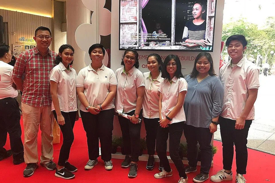 TIMBA PENGALAMAN BARU: Pelajar ITE Kolej Timur termasuk jurugambar Cik Renny Nadira Zufrie (tiga dari kiri) dan penyunting video Cik Nur Kamilia Aswan (tiga dari kanan) bergambar di hadapan video mereka yang dipaparkan semasa pameran foto Palang Merah Singapura. Bersama mereka ialah pensyarah mereka Cik Syabanun Zainudin (dua dari kanan) dan Encik Muhammad Suffian Zainuddin (paling kiri) - Foto ihsan SYABANUN ZAINUDIN