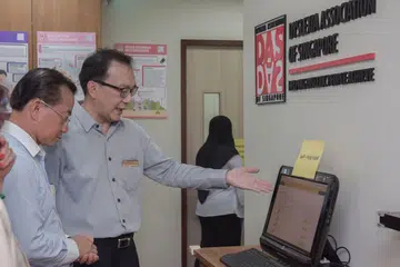 PUSAT PEMBELAJARAN BARU: Anggota Parlimen GRC Marine Parade, Encik Seah Kian Peng (kiri), dibawa melihat pusat Persatuan Disleksia Singapura (DAS) yang baru di Serangoon semalam. - Foto BH oleh LEE JIA WEN