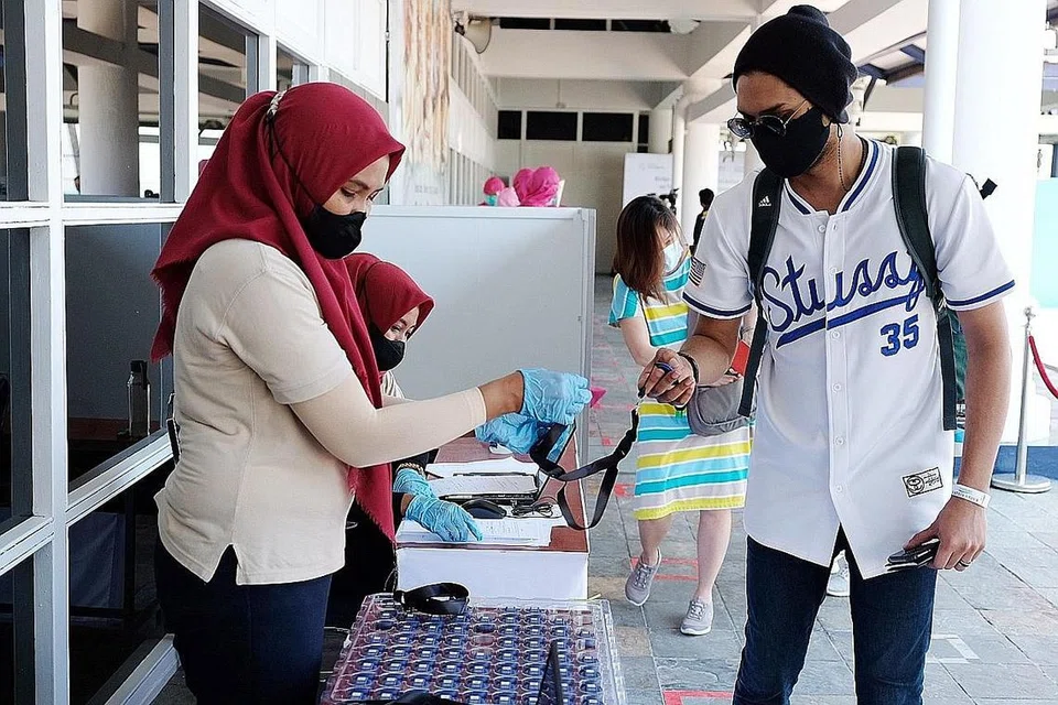 JALANI UJIAN: Wartawan (atas, kanan) dibawa ke kaunter pemeriksaan untuk melakukan ujian PCR dan mengambil token pas biru - yang serupa token 'Trace Together' di Singapura setibanya di Bintan. - Foto BM oleh KHALID BABA 