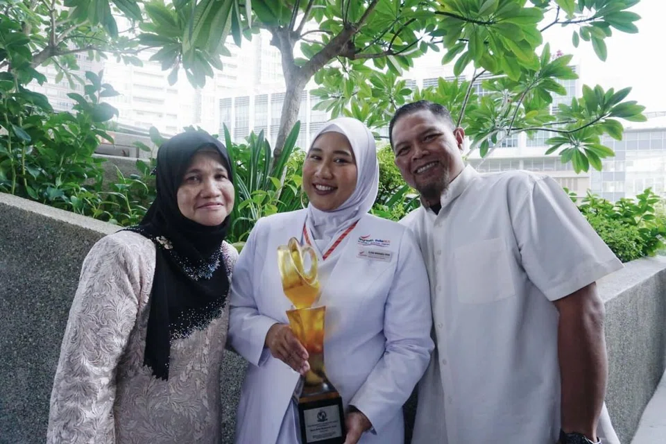 Cik Elena Mohamed Ayob (tengah) bersama ibu, Cik Norsiah Abu Kassim (kiri) dan suami, Encik Othman Abdul Rashid (kanan), semasa majlis Anugerah Presiden bagi Jururawat 2024 yang diadakan di The Star Gallery, Star Vista. 