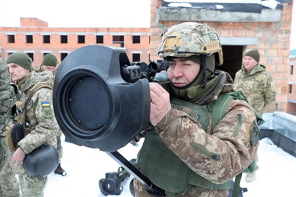 SALING ADAKAN LATIHAN TENTERA: Seorang askar Ukraine mengacukan senjata antikereta kebal yang dibekalkan Britain kelmarin (gambar atas) sedang Russia pula mengadakan latihan melibatkan kenderaan berperisai jenis BMP-3 di daerah Rostov pada hari yang sama. - Foto REUTERS