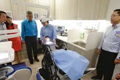 POLIKLINIK DIPERTINGKAT: Perdana Menteri Lee Hsien Loong (tiga dari kiri) yang ditemani (dari kiri) Menteri Negara Kanan (Kesihatan merangkap Pengangkutan), Dr Lam Pin Min; CEO NHGP Profesor Madya Chong Phui-Nah; serta Pengarah Perkhidmatan Dental NHGP Dr Kenneth Low (kanan) memerhatikan penggunaan penyondong kereta roda di Poliklinik Ang Mo Kio yang dipertingkat awal tahun ini. - Foto BH oleh KEVIN LIM