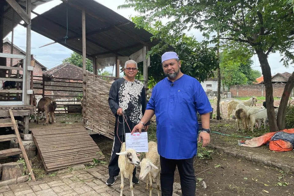 TEMPAH KAMBING: Husin Saaban (kiri) bersama Ustaz Firdaus Masruhen (baju biru) menjalankan ibadah akikah di salah sebuah kandang kambing di Jawa Timur, Indonesia.