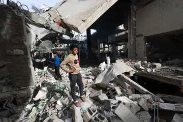 Penduduk Palestin melihat dari dekat bangunan-bangunan yang musnah akibat serangan Israel di Rafah, selatan Gaza.