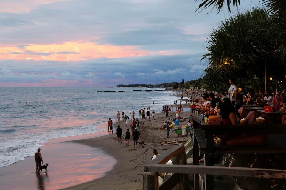 Pelancong menikmati pemandangan matahari terbenam di pantai Canggu di Bali, Indonesia, pada Disember 2021.