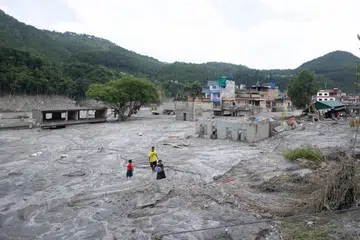 Kanak-kanak berjalan di celah bangunan yang terjejas akibat banjir glasier berhampiran sempadan Nepal-China yang meragut ratusan nyawa, di Trishuli Bazar, Nuwakot, Nepal, pada 31 Ogos.