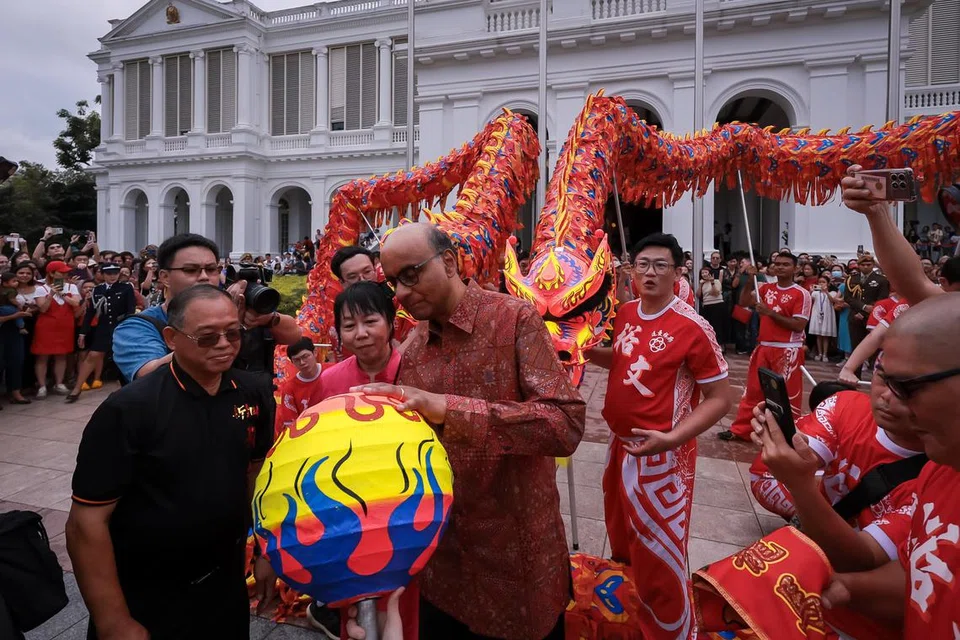 Presiden Tharman Shanmugaratnam (tiga dari kiri) yang ditemani isterinya, Cik Jane Ittogi Shanmugaratnam (dua dari kiri), menandatangani boneka mutiara yang digunakan dalam tarian naga semasa Rumah Terbuka di Istana sempena Tahun Baru Cina pada 12 Februari.